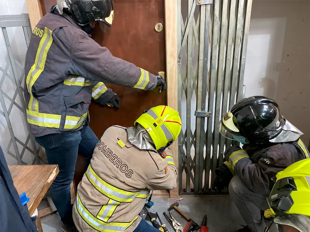 Bomberos practicando técnicas de apertura rápida de puertas durante formación del Método Katana con EPIs y herramientas especializadas.